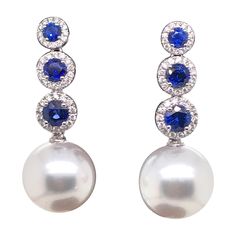 18K White gold drop earrings featuring 6 blue sapphires, 1.50 carats, flanked with round brilliants weighing 0.37 carats and two South Sea Pearls measuring 12-13 mm Color G-H Clarity SI Elegant Blue Gia Certified Diamond Earrings, Blue Pearl Earrings Fine Jewelry For Formal Events, Blue Pearl Earrings For Formal Events, Blue Pearl Earrings For Formal Occasions, Formal Round Sapphire Diamond Earrings, Elegant Blue Round Diamond Earrings, Luxury Blue Pearl Earrings For Anniversary, Classic Blue Round Pearl Earrings, Classic Blue Pearl Earrings For Anniversary