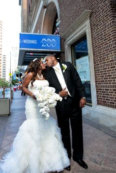 a bride and groom kissing on the street