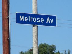 a blue street sign sitting on the side of a pole next to power lines and trees