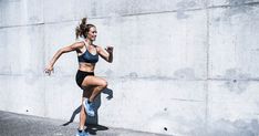 a woman running down the street in front of a concrete wall