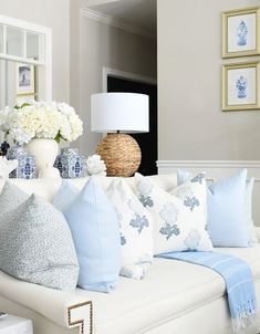 a living room filled with lots of white and blue pillows on top of a couch