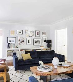 a living room with blue couches and pictures on the wall above them, along with a coffee table