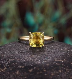 a yellow diamond ring sitting on top of a rock