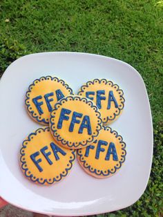 four decorated cookies sitting on top of a white plate in front of some green grass