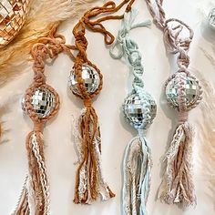 several tassels with disco balls hanging from them on a white table cloth covered surface