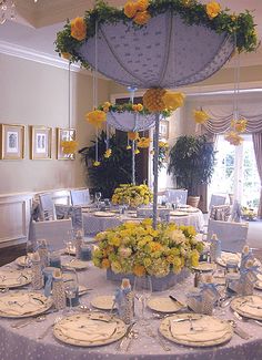 a dining room table is set with yellow flowers and place settings for an elegant dinner