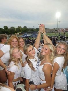 the cheerleaders are posing for a photo at a football game with their hands in the air