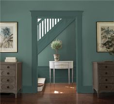 a room painted in blue and green with a vase on the table next to it