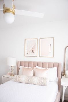 a bed with white sheets and pillows in front of two framed pictures on the wall