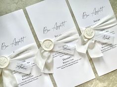 three wedding programs with white ribbons and wax stamp on the front, one for bridal