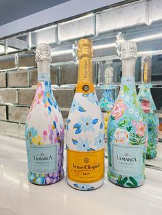 three bottles of wine sitting on top of a counter in front of a tiled wall