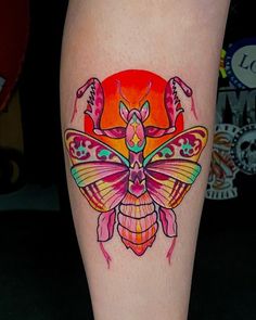 a colorful tattoo design on the leg of a woman's leg, with an insect