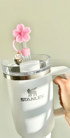 a hand holding a blender with a pink flower on the top and two rings attached to it