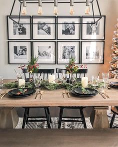 a dining room table decorated for christmas with candles, greenery and pictures on the wall