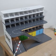 a toy model of a building with an airplane on the roof and parking lot below it