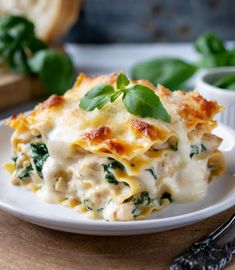 a white plate topped with lasagna covered in cheese and spinach