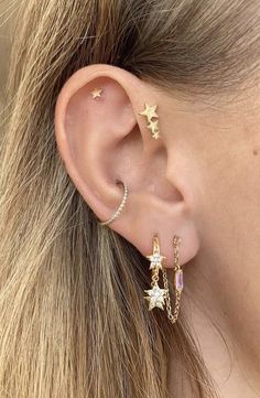 a woman wearing gold stars and chain ear cuff with an earring on her left side