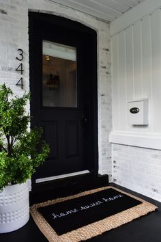 a black door with a welcome mat and potted plant