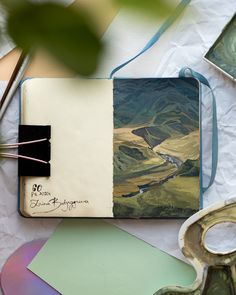 an open book on top of a table next to scissors and other items