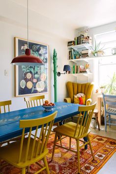 a dining room with yellow chairs and a blue table