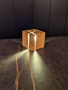 a wooden box with a light coming out of it on top of a marble table