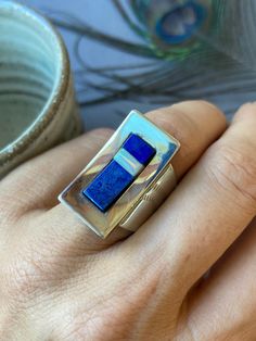 This wonderful statement ring was made by the popular design company, Desert Rose Trading Company. It has Western and Tribal design elements and has been crafted in sterling silver with lapis lazuli and synthetic opal inlay. The ring has wonderful coverage on the finger and would likely fit up to a full size smaller than what's listed. The total weight is 13 grams and the face measures one inch long. Inside the ring is stamped DTR China 925. The ring measures a US size 8  To view similar items return to our shop here- https://www.etsy.com/shop/Luere Your jewelry will come beautifully packaged and ready to give as a gift. Each piece comes in a hand decorated brown paper gift box wrapped with love! For multiple purchase orders - Please let me know in the "notes to seller" upon checkout if yo Modernist Inlay Jewelry As Gift, Modernist Rings With Inlay For Gift, Modernist Rings With Inlay Perfect For Gifts, Modern Sterling Silver Opal Ring Gift, Modern Sterling Silver Opal Ring For Gift, Modern Blue Opal Ring Gift, Modern Blue Opal Ring For Gift, Inlay Rings, Vintage Desert