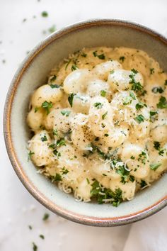 a bowl filled with macaroni and cheese covered in parsley