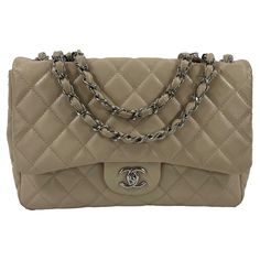 From the 2008 collection. This classic Chanel flap handbag is crafted with beige quilted lambskin leather and silver-toned hardware. The flap opens using an interlocking CC turn-lock to one compartment lined in a smooth beige leather with a slip pocket and zipper pocket inside. A patch pocket is located on the backside exterior. The strap is composed of a chain with a beige leather strip intertwined. It can be lengthened to wear as a crossbody or shortened to wear as a shoulder handbag. Measurem Chanel Classic Flap Lambskin, Silver Shoulder Bag, Chanel Maxi, Classic Chanel, Chanel Jumbo, Shoulder Handbag, Quilted Leather, Classic Flap, Chanel Handbags