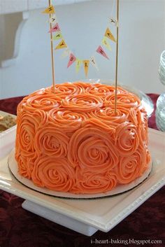 a birthday cake with orange frosting and bunting on top is sitting on a white plate