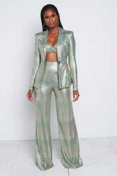 a woman standing in front of a white wall wearing a green suit and matching pants