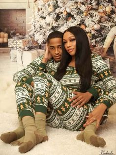 a man and woman sitting in front of a christmas tree wearing matching ugly sweaters