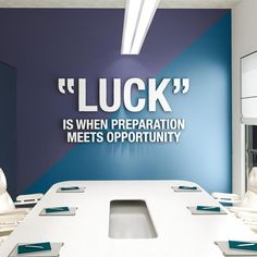 a conference room with blue walls and white tables in front of a large sign that says luck is when preparation meets opportunity