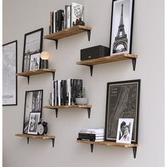 some shelves with pictures, books and other items on them against a wall in a living room