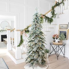 a decorated christmas tree sitting in the middle of a living room next to a staircase