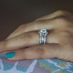 a woman's hand with two wedding rings on her left and the other hand holding an engagement ring