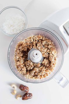 a food processor filled with granola and nuts on top of a white countertop