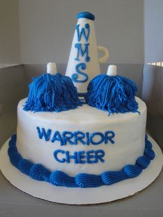 a white cake with blue frosting and decorations on top that says warrior cheer in large letters