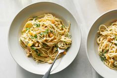 two white bowls filled with pasta and garnished with parsley