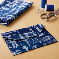 a pair of scissors sitting on top of a table next to a blue cloth bag