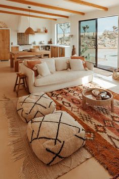 a living room filled with lots of furniture and large windows overlooking the water in front of it