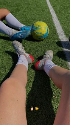 two soccer players are laying on the grass with their feet propped up next to each other