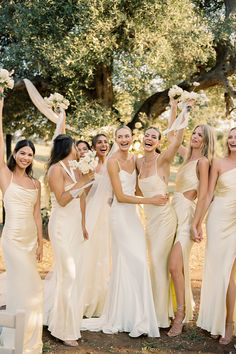 a group of women standing next to each other in front of a tree with flowers