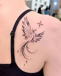 a woman's shoulder with a bird tattoo on her left shoulder and stars in the back