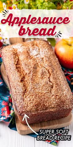 a loaf of bread sitting on top of a wooden cutting board next to an apple