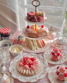 a table topped with plates and cakes covered in frosted icing next to a window