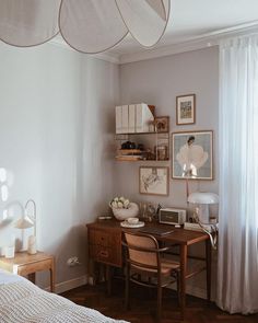 a bedroom with a bed, desk and pictures hanging on the wall in front of it