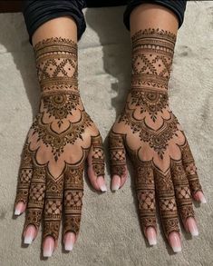 two hands with henna tattoos on them, one is showing off the intricate design