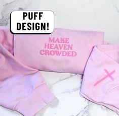 two pink onesuits with the words make heaven crowded printed on them, sitting next to each other