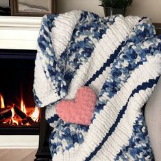 a blanket with a heart on it next to a fire place