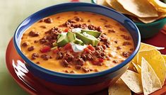 a bowl of chili cheese soup with tortilla chips